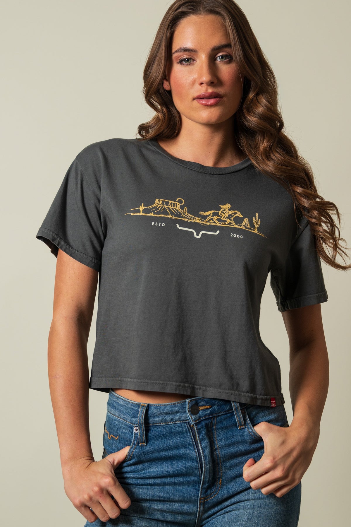 Kimes Ranch Go West short sleeve crop tee in Pepper with gold graphic showing cowboy, landscape, and ESTD 2009