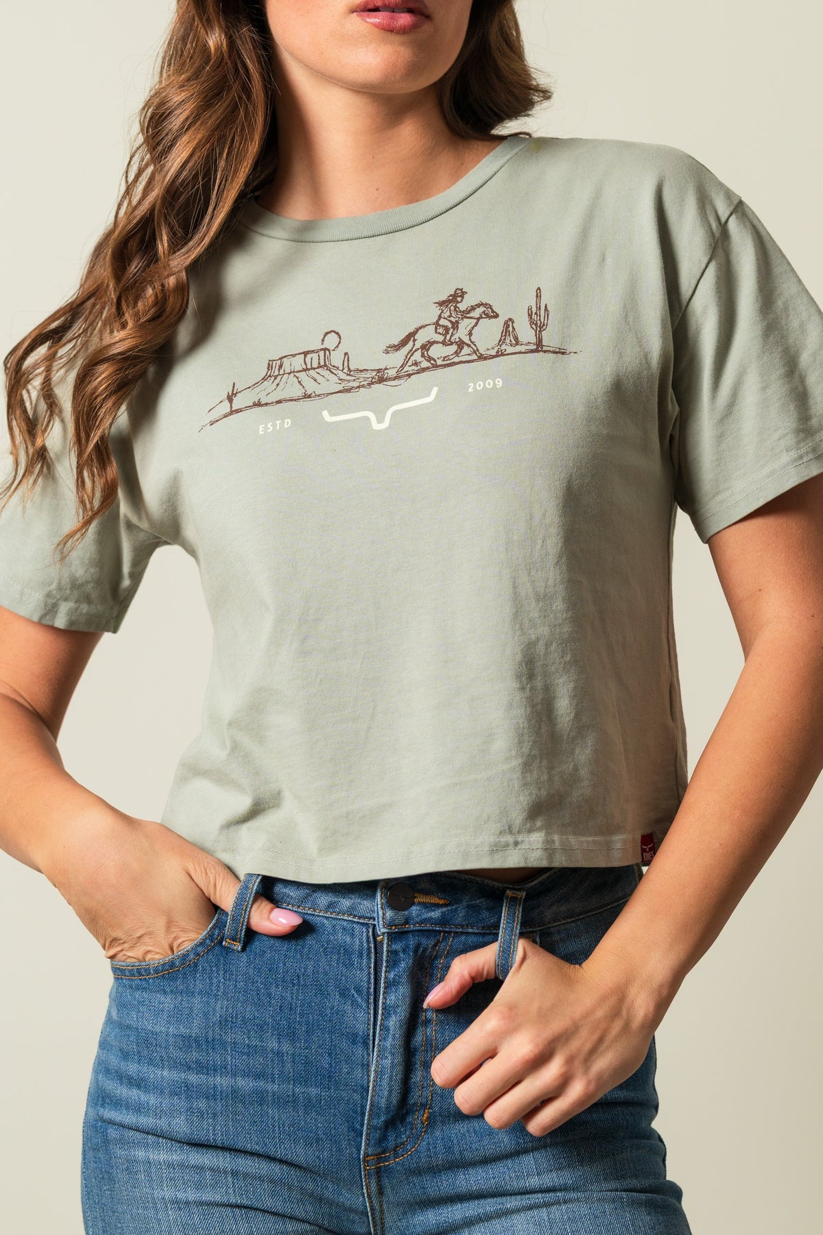 Kimes Ranch Go West sage short sleeve shirt with cowgirl and cactus graphic, 'ESTD 2009', and stylized steer logo
