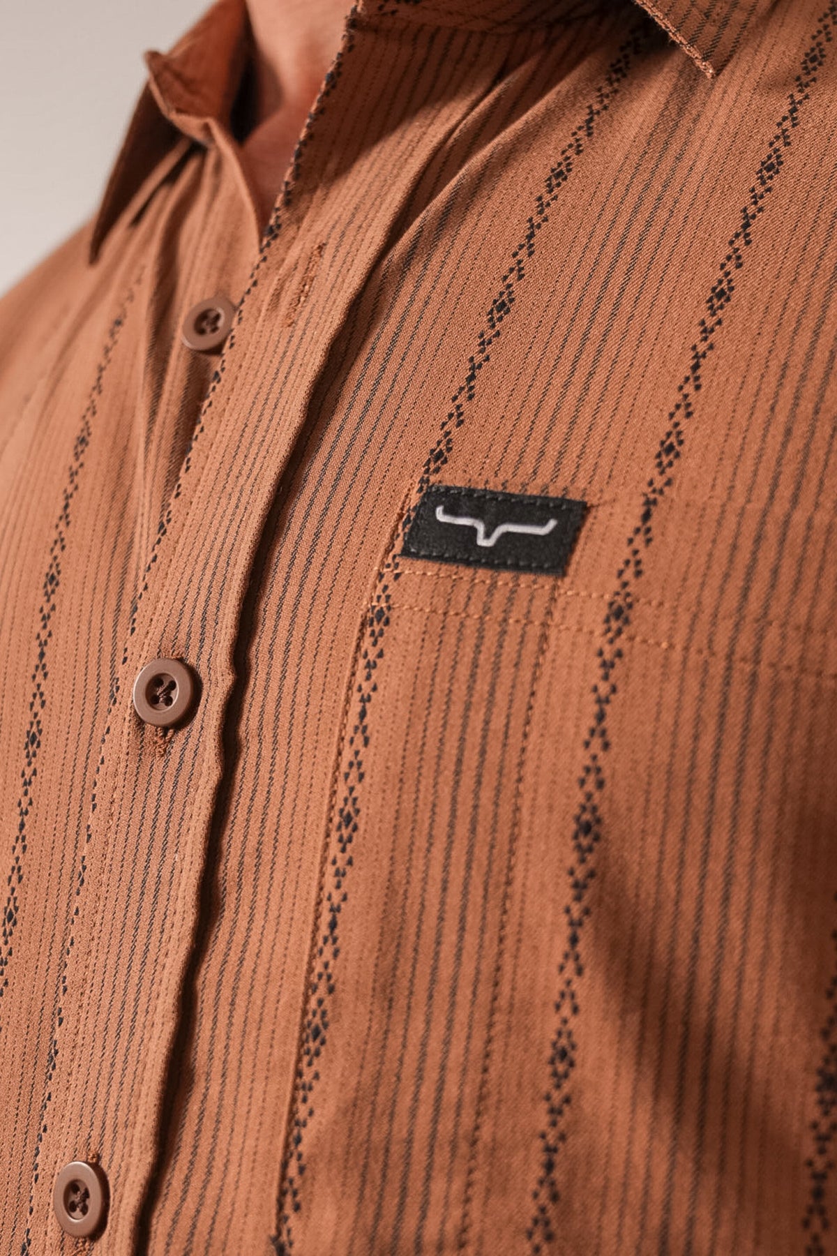 Kimes Ranch Hanover dress shirt in brown with vertical stripes, button placket, and chest pocket logo