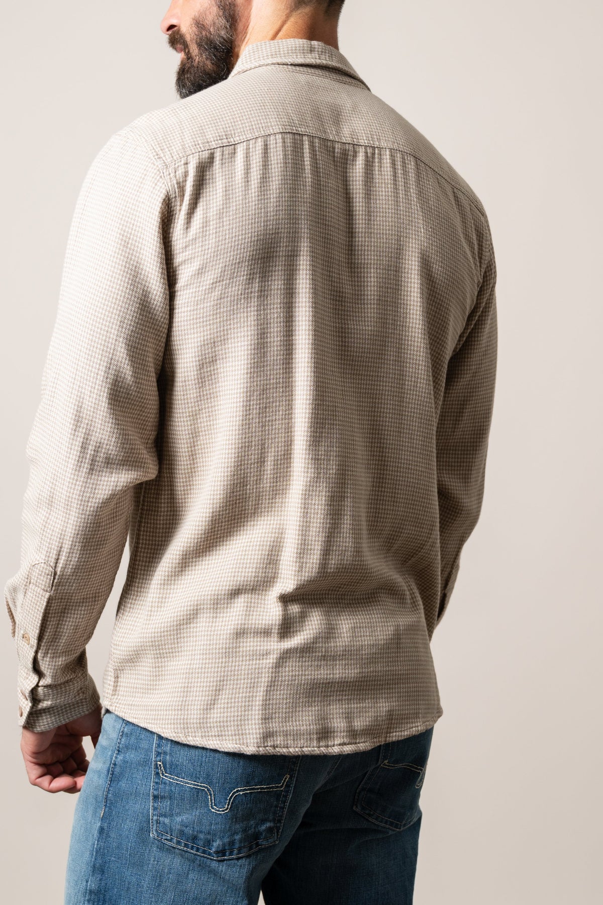 Kimes Ranch Kelso dress shirt in Natural with back yoke and button cuffs, shown from behind on a model wearing blue jeans