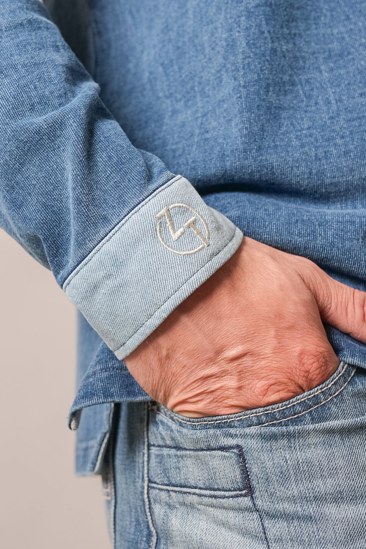Kimes Ranch ZT Rugger polo in indigo denim, showing long sleeve with contrasting cuff embroidered with the Kimes Ranch logo