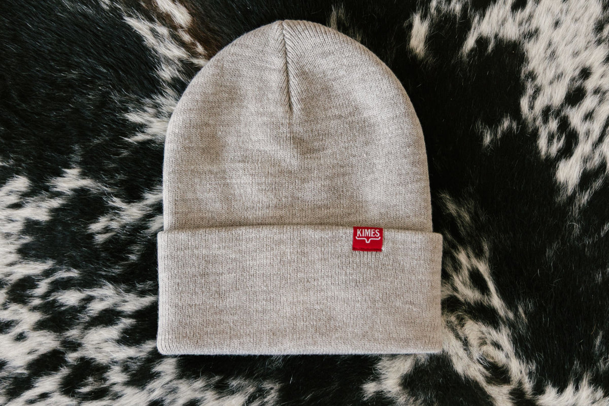 Kimes Ranch KR Clipped Hat in Oatmeal Heather with a red logo patch on the folded cuff