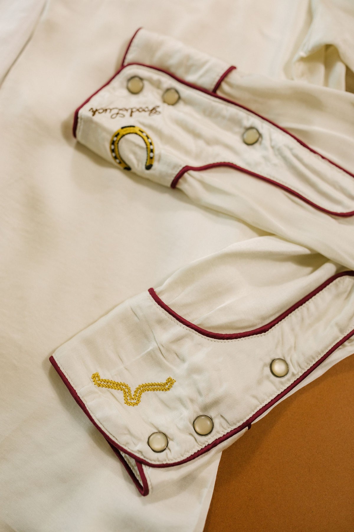 Kimes Ranch Merada top in Soft Gold, close-up, with embroidered horseshoe and lariat on the cuffs with red trim