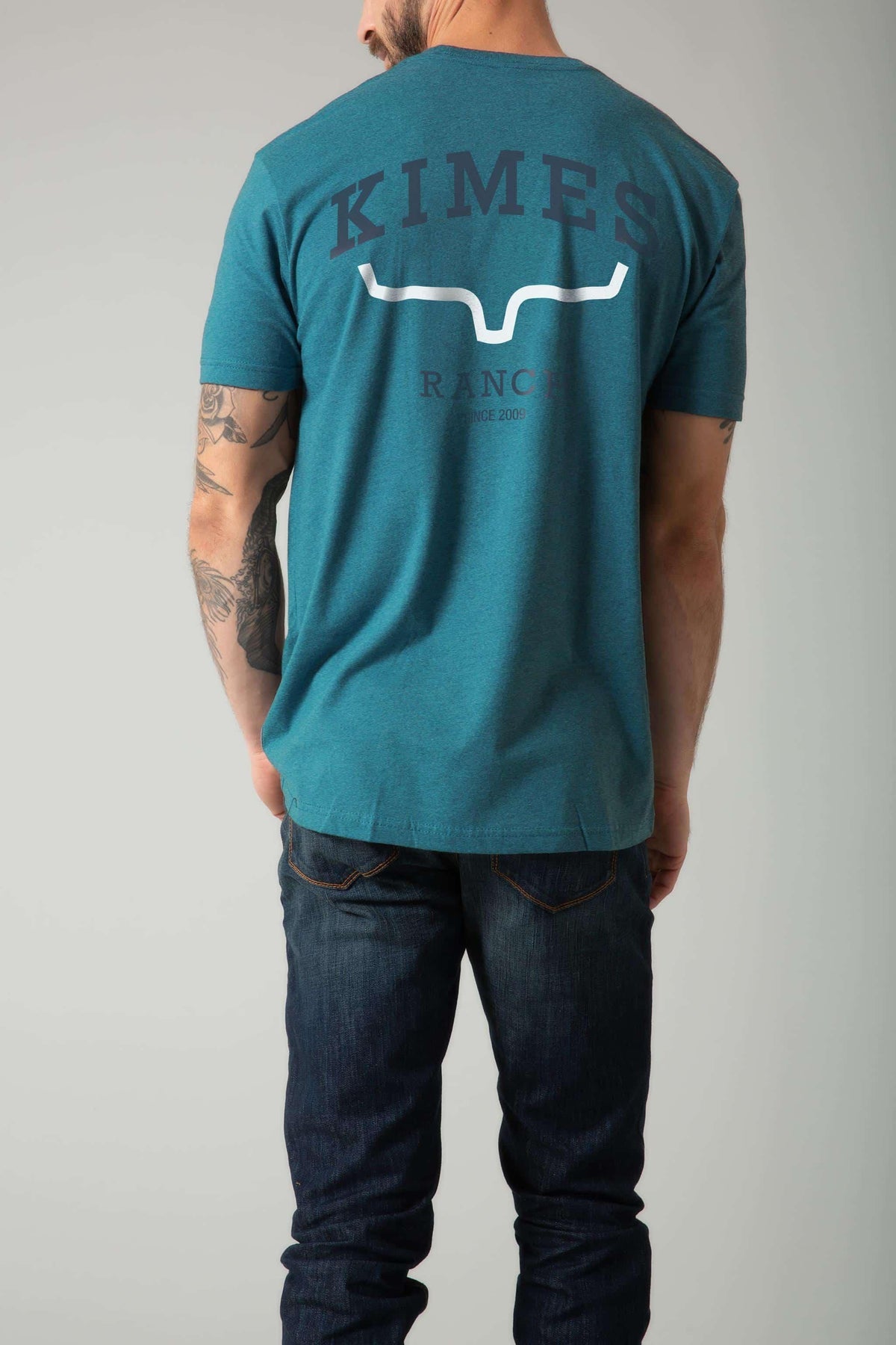 Kimes Ranch Since 2009 Shirt in Teal, back view, with a back graphic featuring the Kimes Ranch logo and text