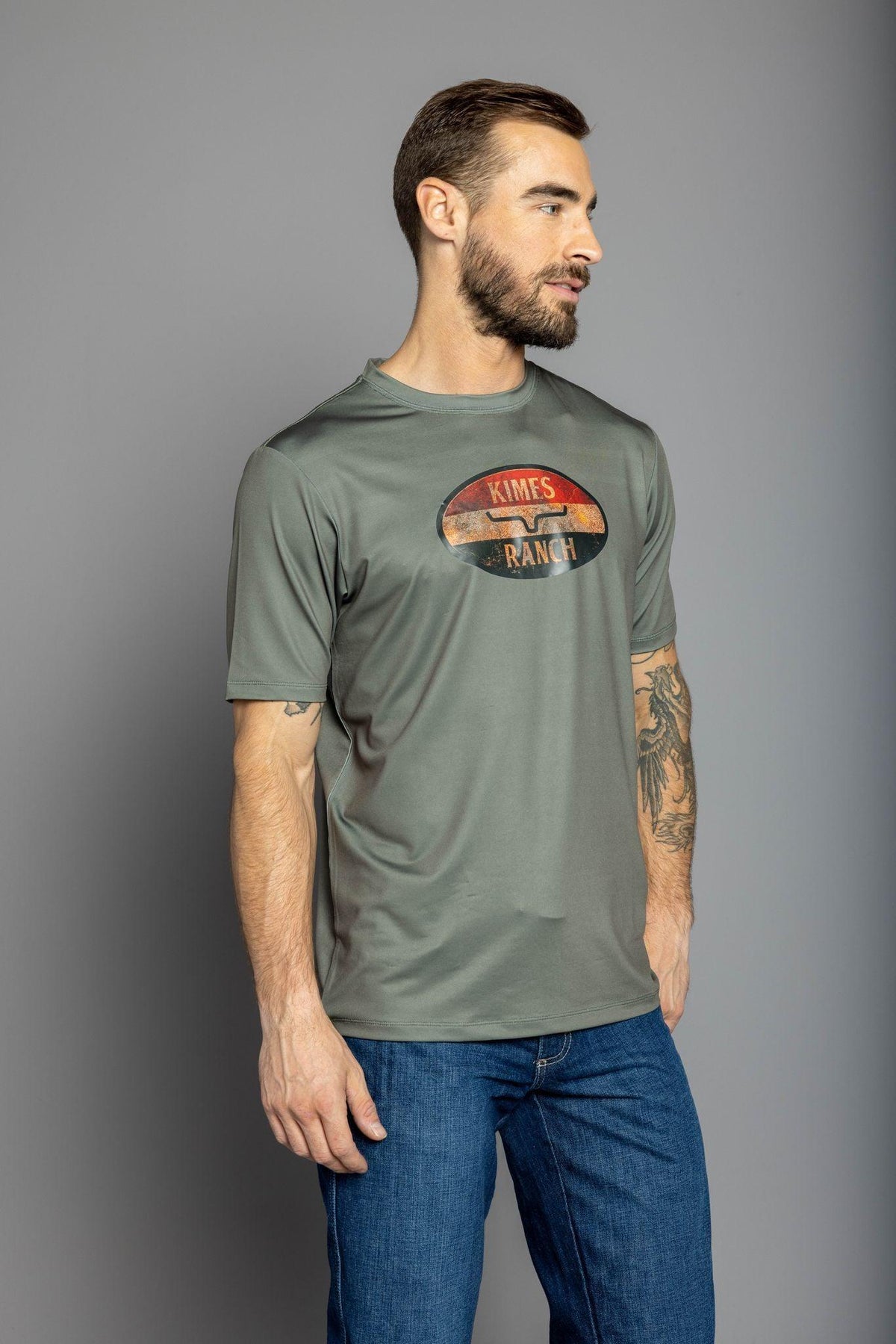 Kimes Ranch American Standard Tech T-Shirt in Sage, side view, with a vintage oval Kimes Ranch logo on the chest