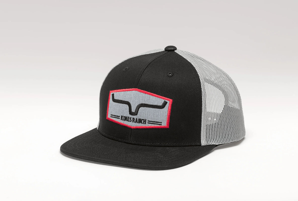 Kimes Ranch Replay Trucker Hat in Black, side view, with a grey mesh back and red outlined logo patch