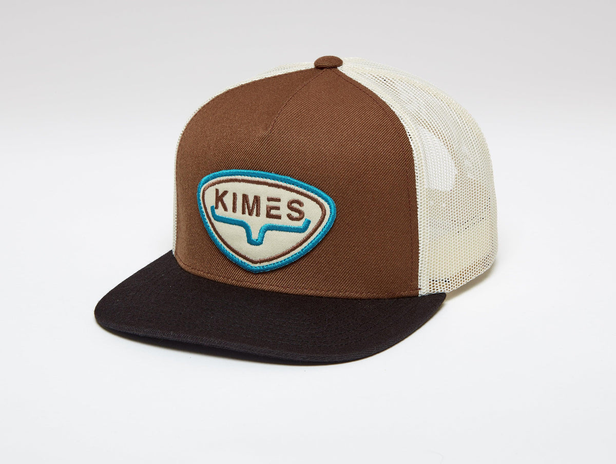 Kimes Ranch Conway Trucker Hat in Brown with a front embroidered logo patch and a flat brim