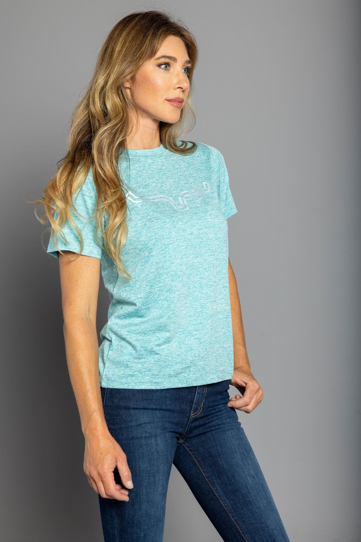 Kimes Ranch Ladies Outlier Tech Tee Shirt in Light Blue Heather, side view, with a white outline steer logo on the chest